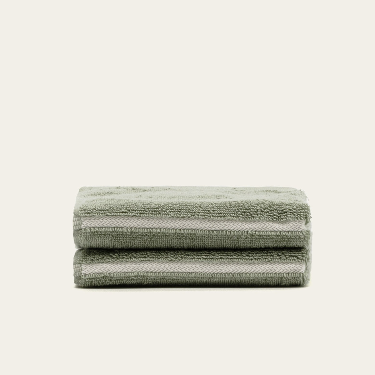Stack of sage green cotton towels with ribbed texture, folded