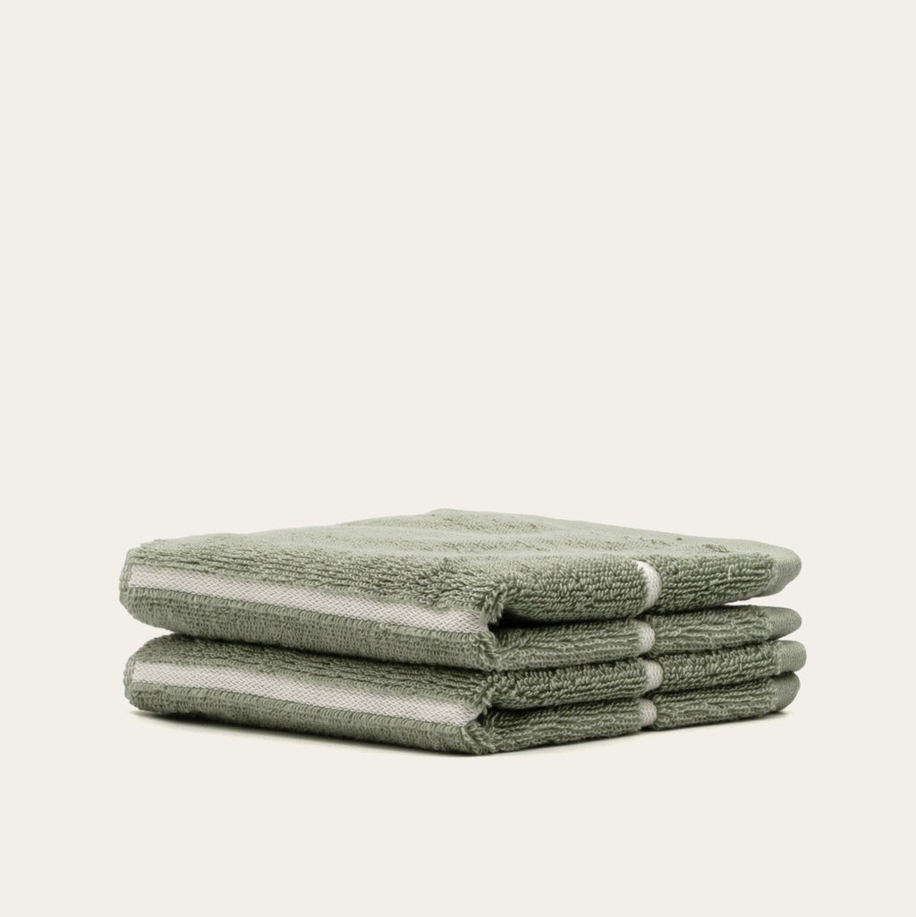 Folded sage green cotton towels stacked together