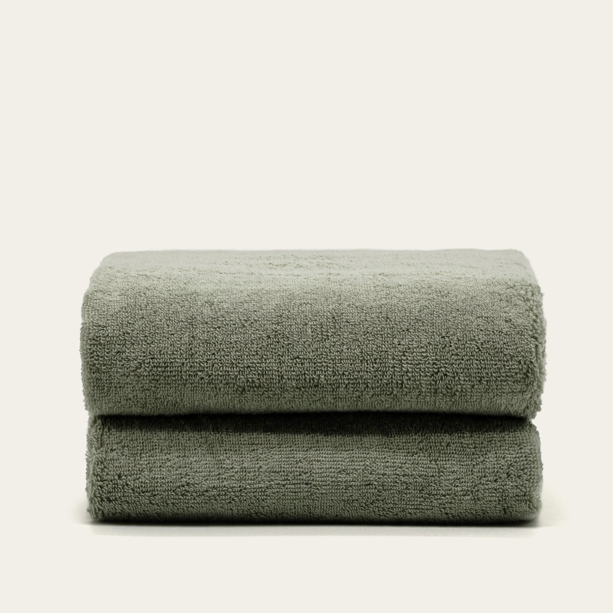 Single folded sage green cotton towel with soft terry texture