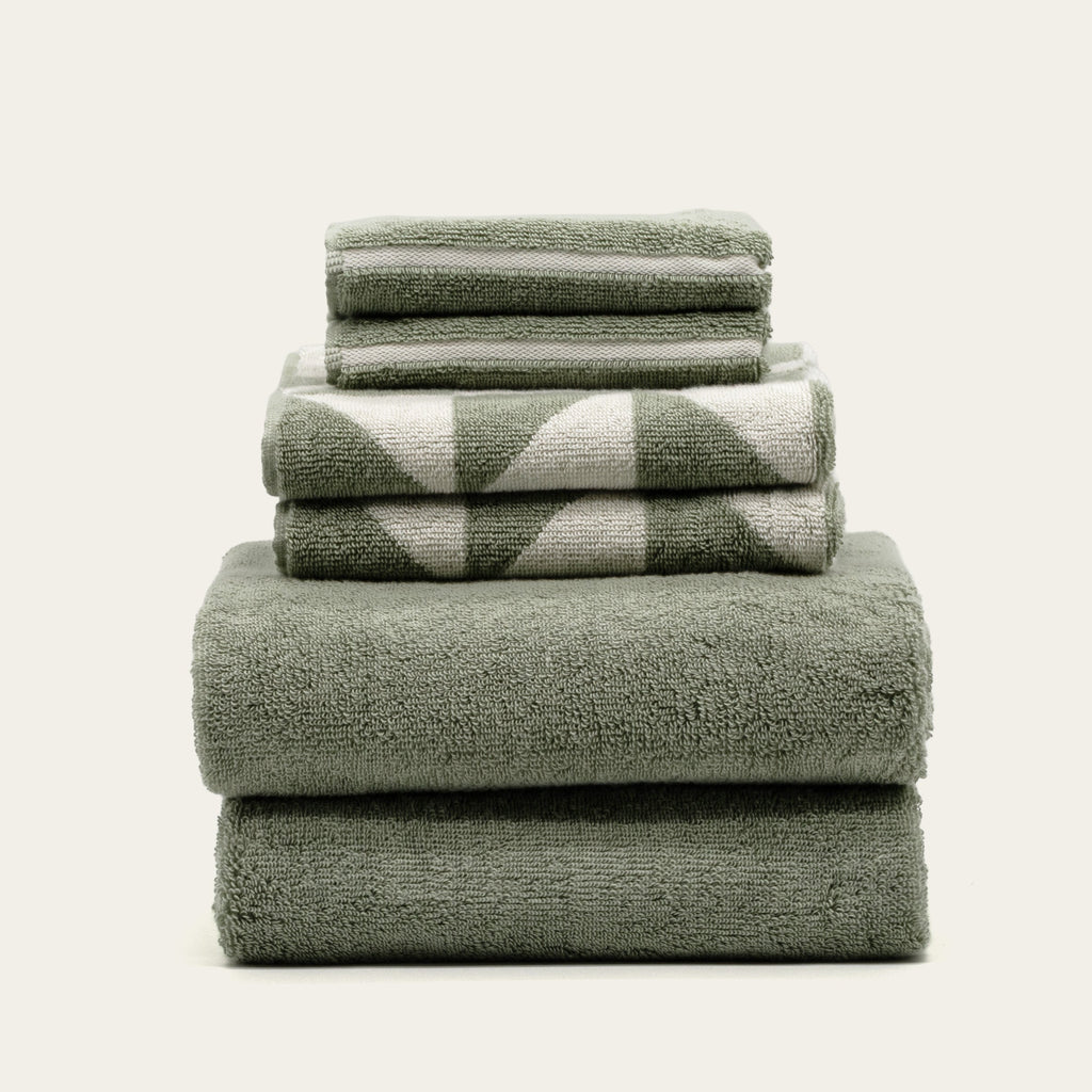 Stack of sage green cotton towels with ecru check and stripe detailing