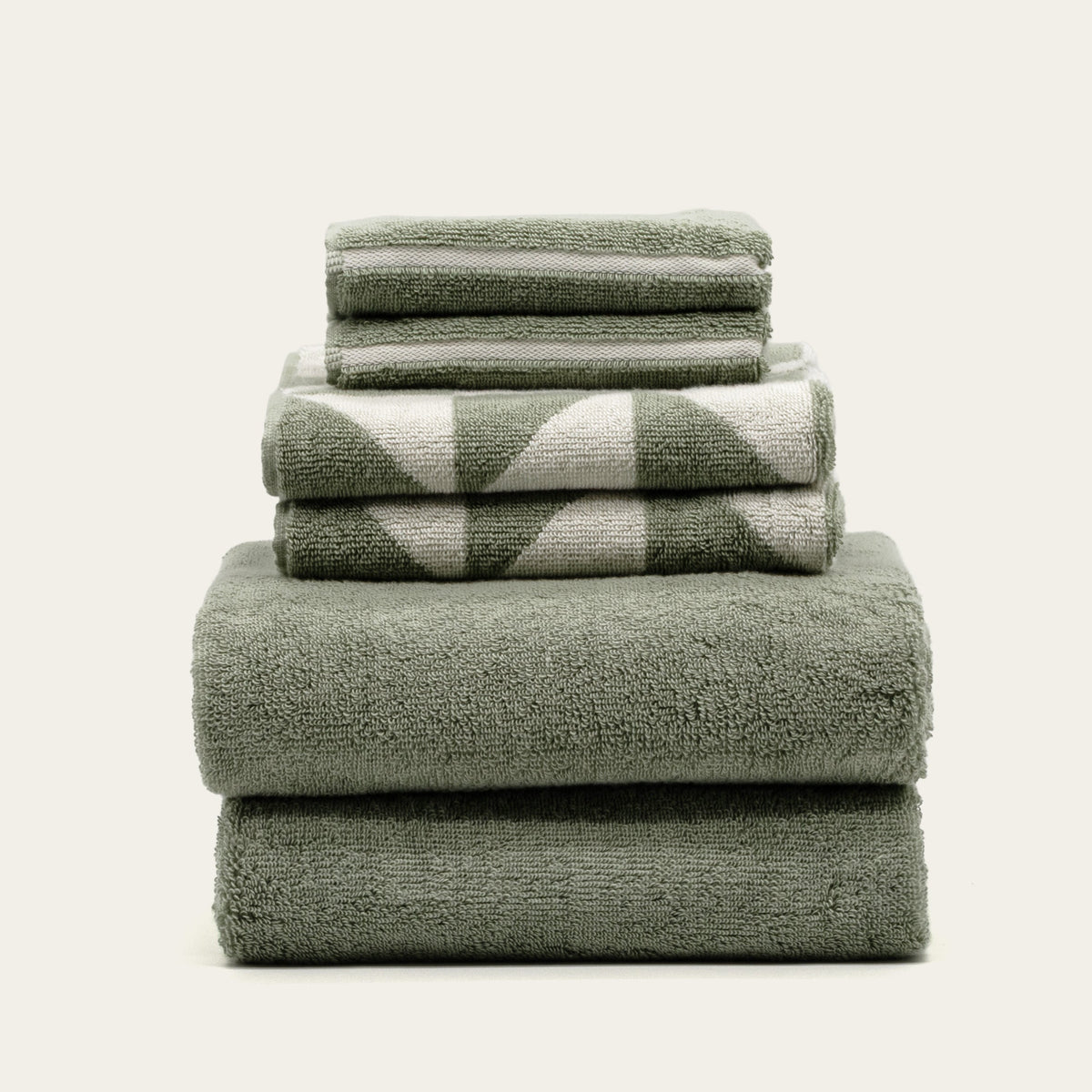 Stack of sage green cotton towels with ecru check and stripe detailing