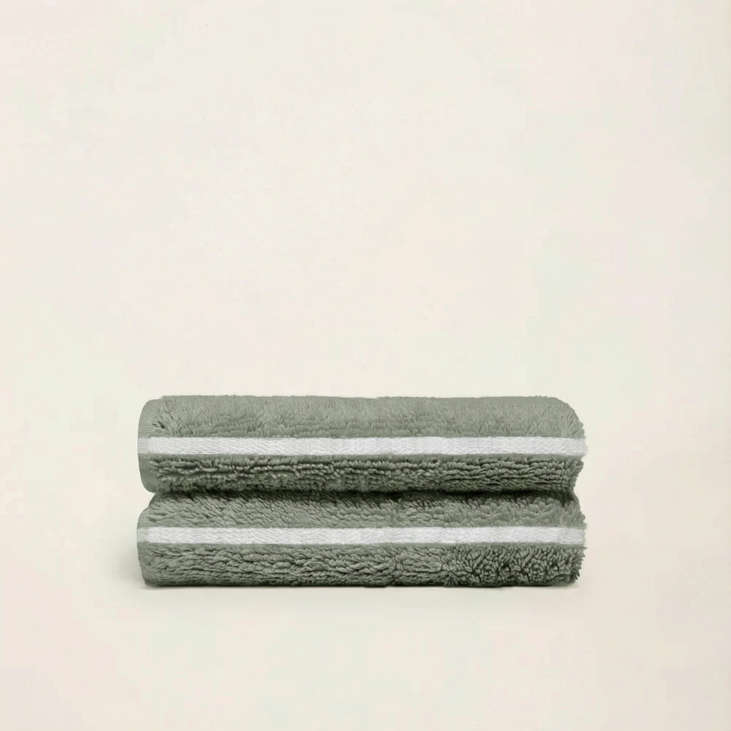 Sage green cotton towels, folded stack with textured terry loops and striped trim