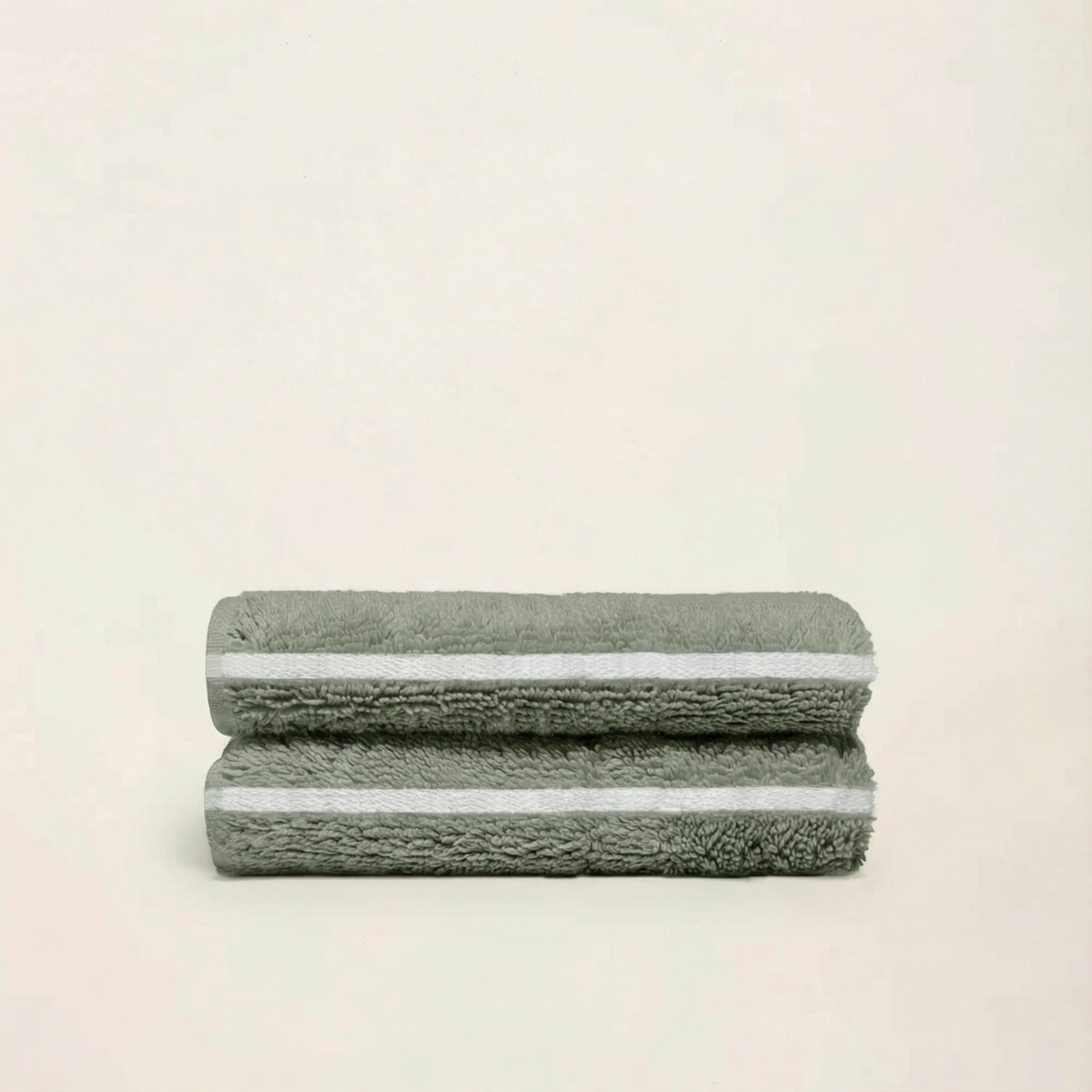 Sage green cotton towels, folded stack with textured terry loops and striped trim