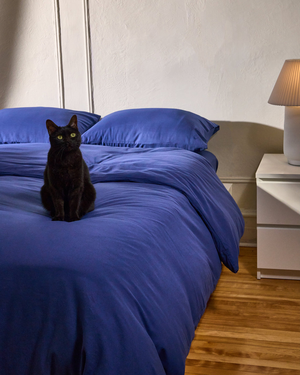 Milk fibre pillowcase set in dark blue with matching pillowcases on a bed