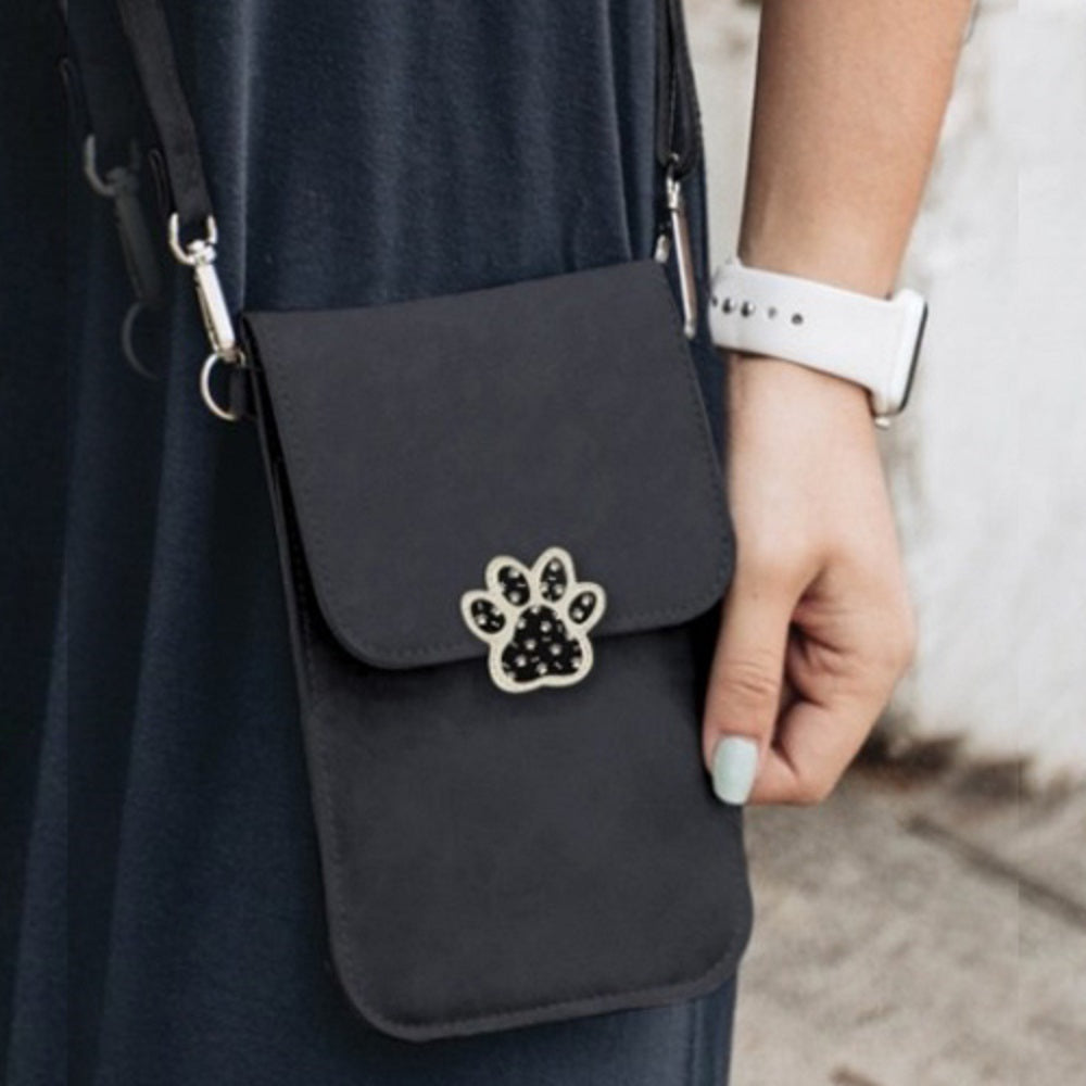 Black dog paw phone crossbody pouch held by hand, featuring a silver paw emblem