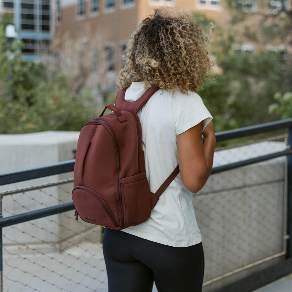Wine-brown diaper backpack worn with padded shoulder straps and front zip pocket