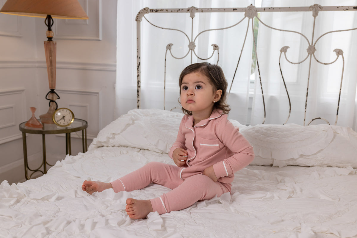 Pink long-sleeve pajama set with button front top and matching pants on child