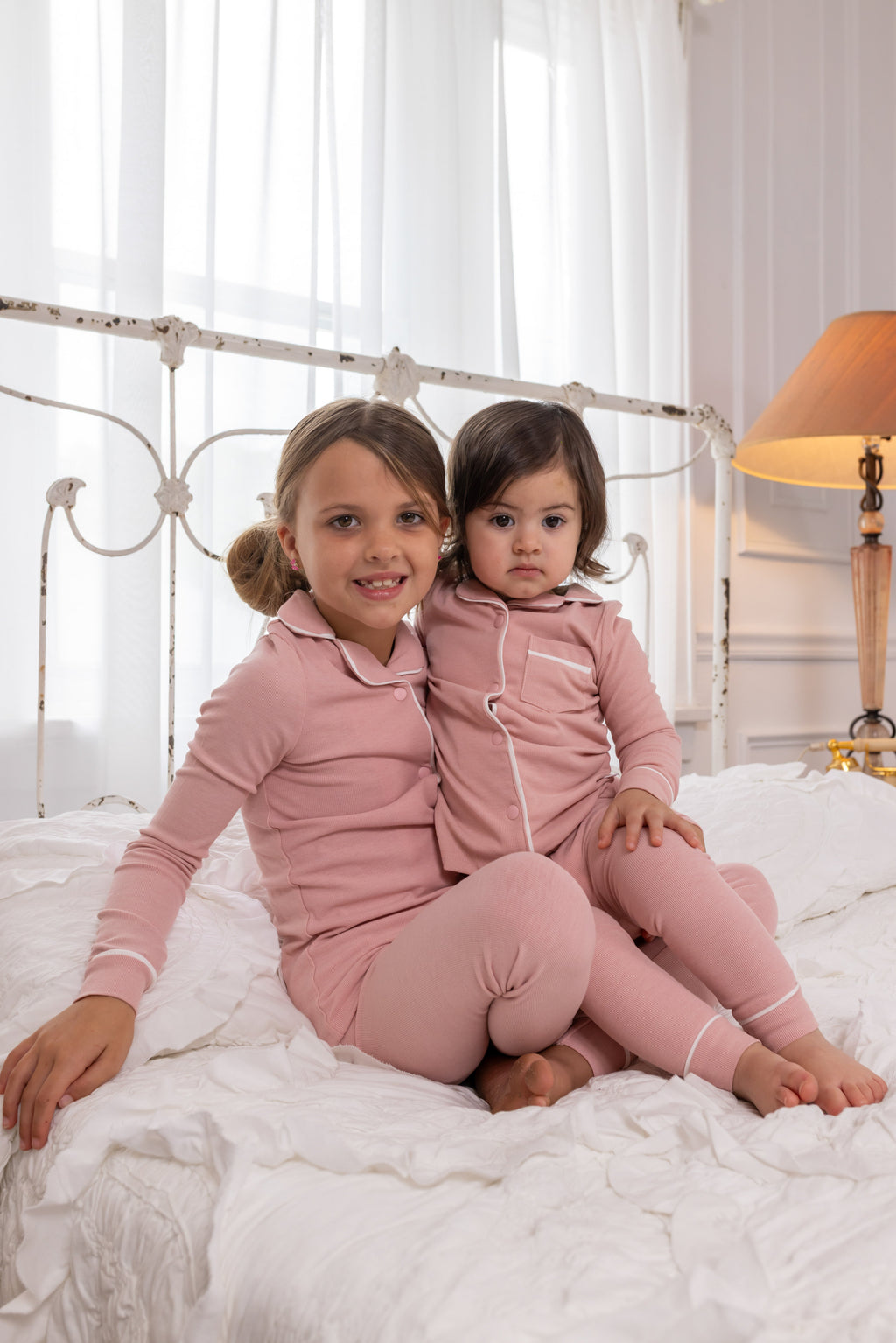 Two children wearing matching pink long-sleeve pajamas with button-front tops