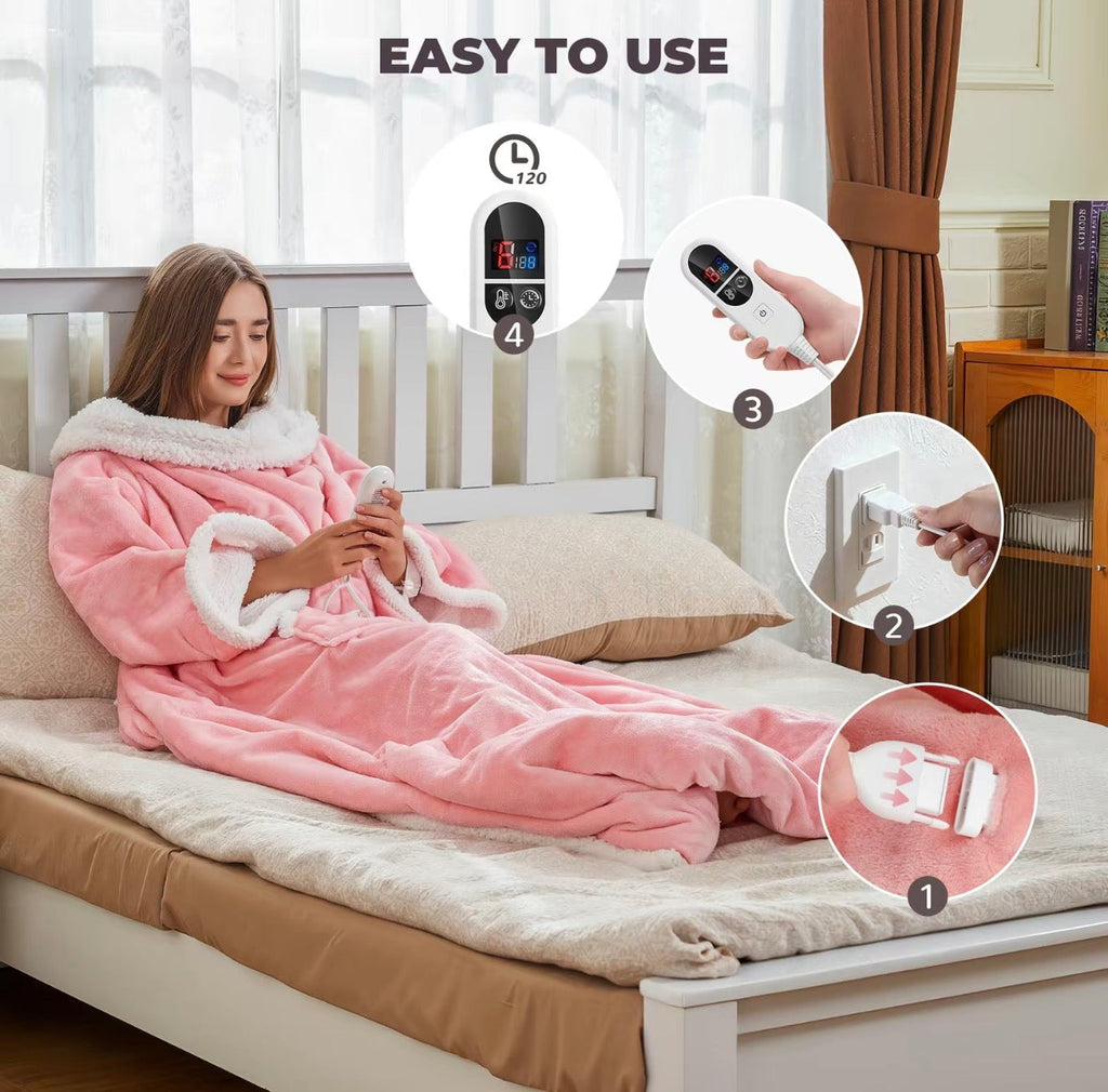 Pink hooded heated wearable blanket with remote controller, laid on bed