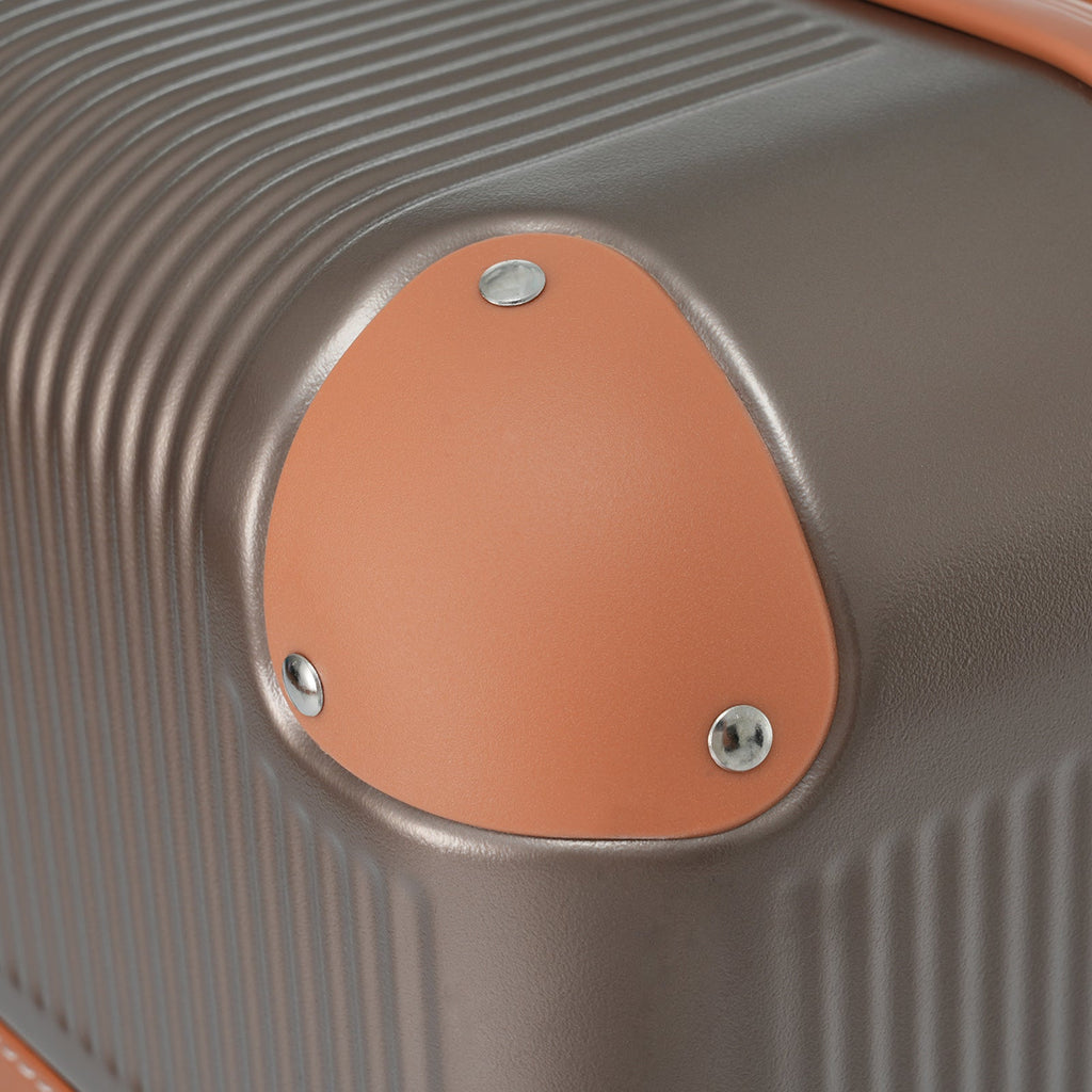 Copper accent handle cover with two screws on ribbed hardshell suitcase
