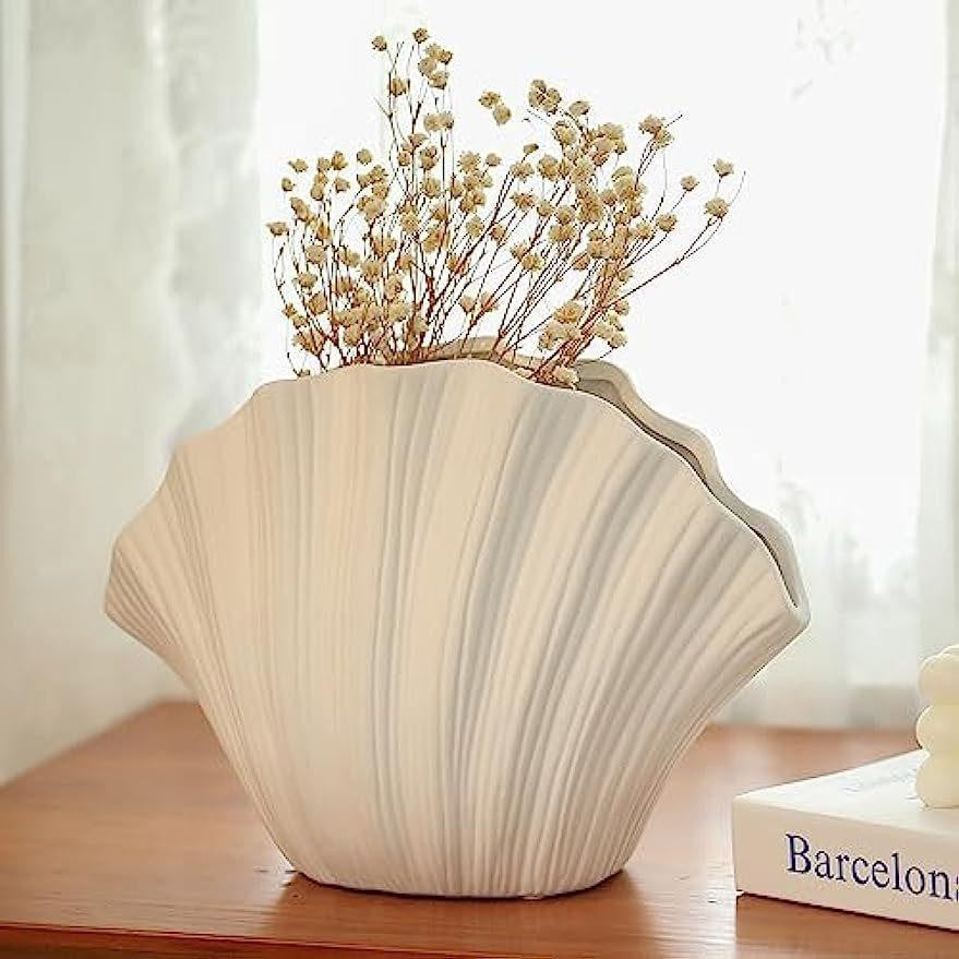 Cream shell-shaped ceramic vase with dried yellow-brown stems for home decor