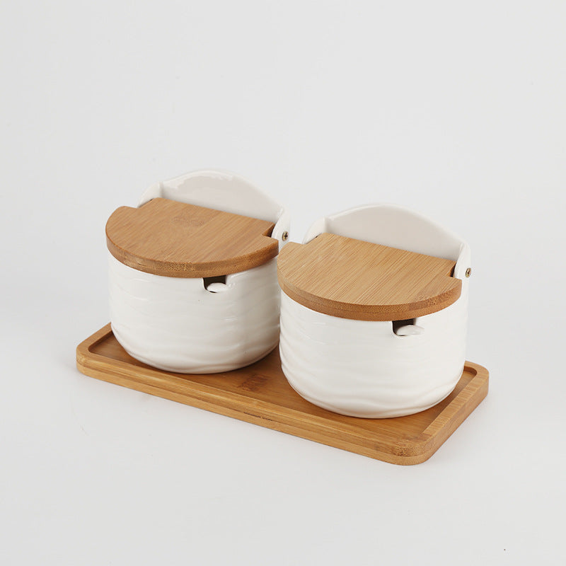 Set of two half-round ceramic seasoning cans with wooden flip-top lids on tray