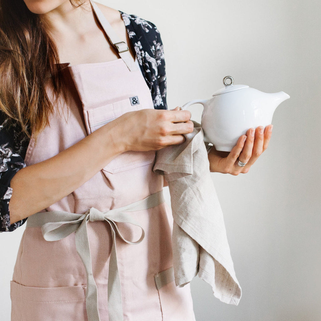 White ceramic teapot with infuser held by a person, metal-lidded top