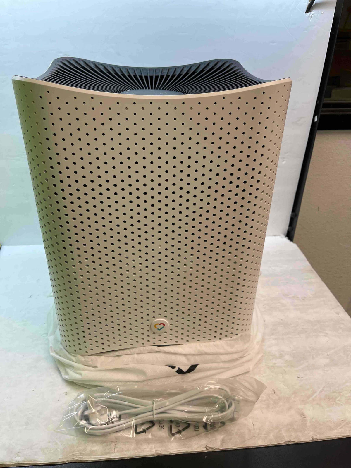 Air purifier with perforated side panel and top fan grille, shown on a tray