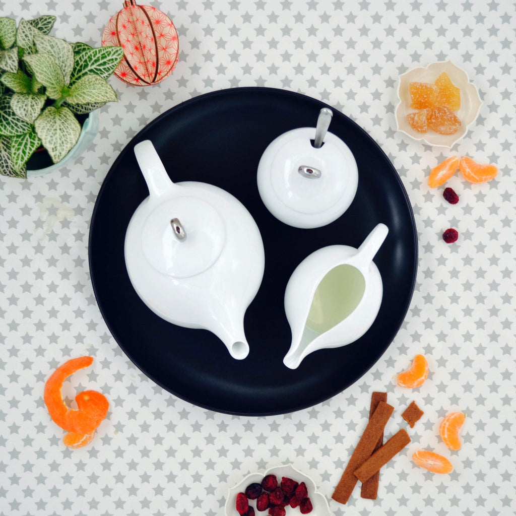 White ceramic sugar bowl with lid and matching creamer on dark tray