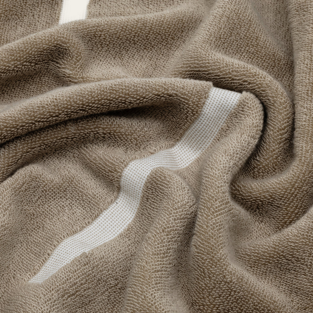 Tan Australian cotton towel with ecru stitched stripe, textured looped fabric detail.