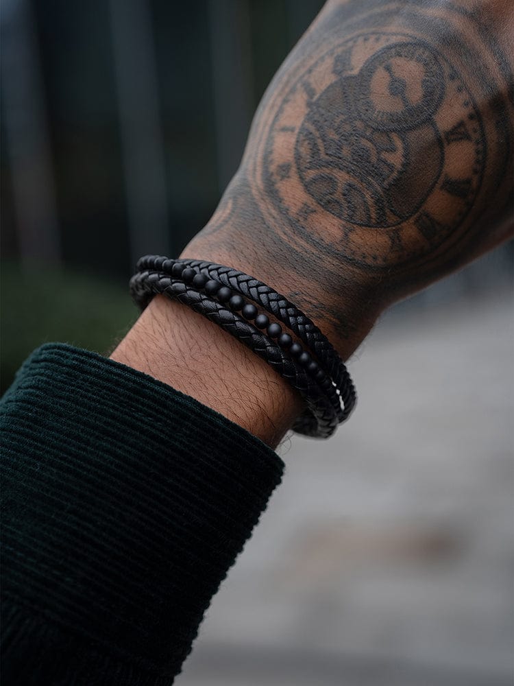 Black braided leather bracelet with bead accents on wrist.
