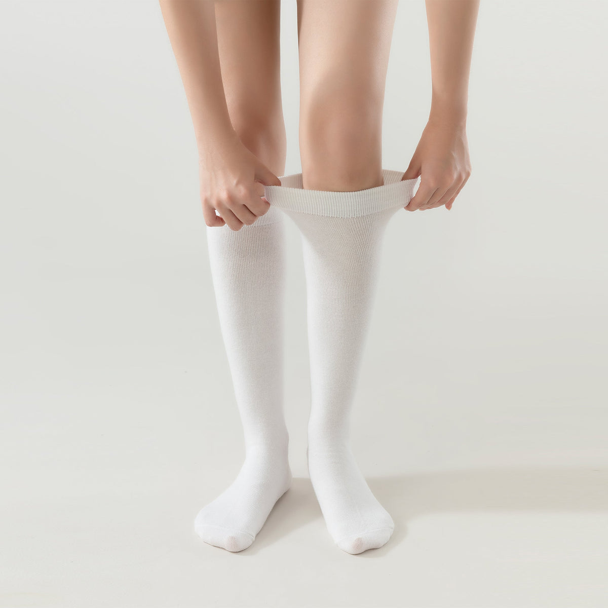 Cream white crew socks being pulled on, ribbed cuff visible
