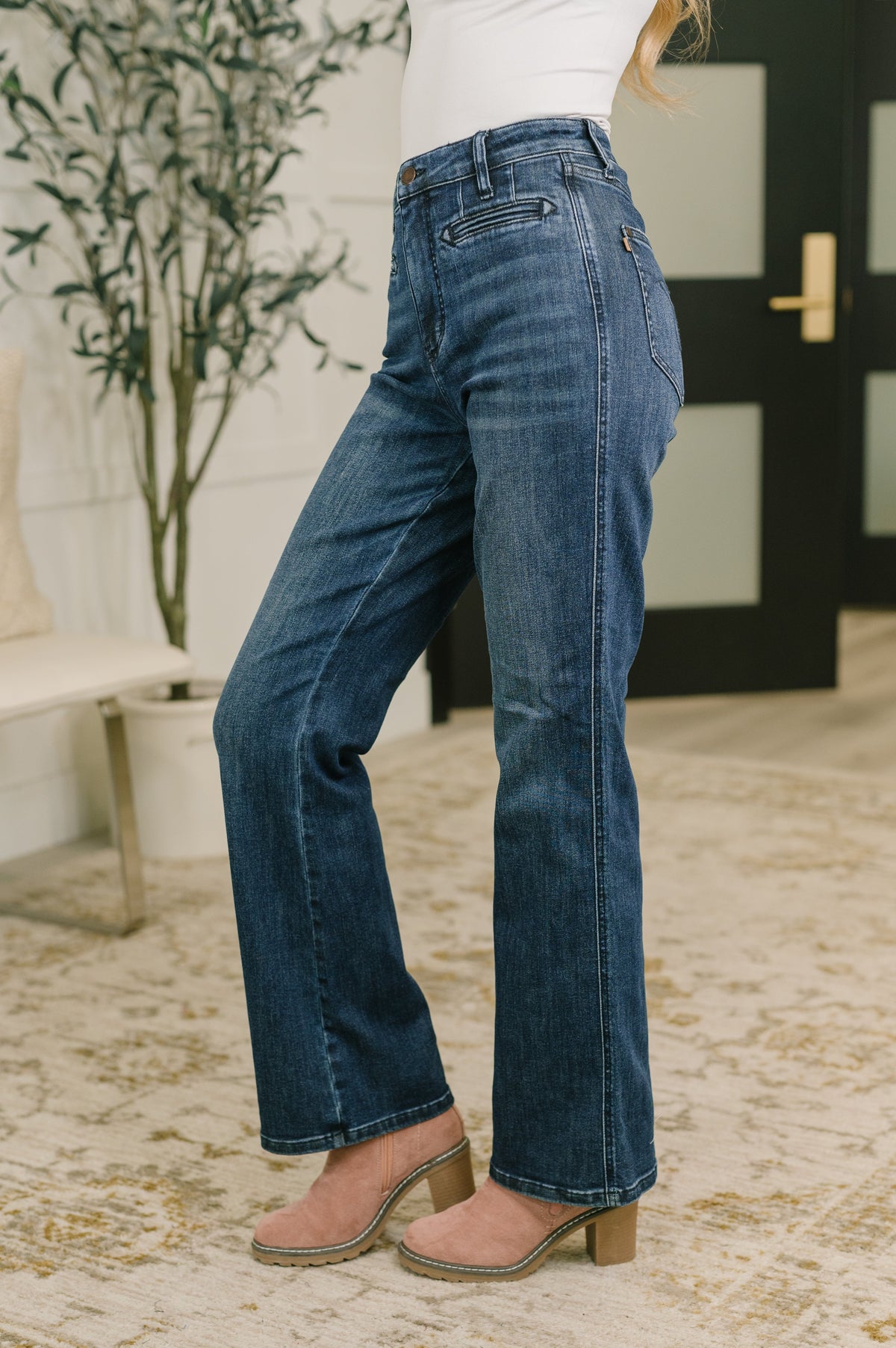 High-waist bootcut jeans in mid-blue denim from the back, with welt pockets and flare