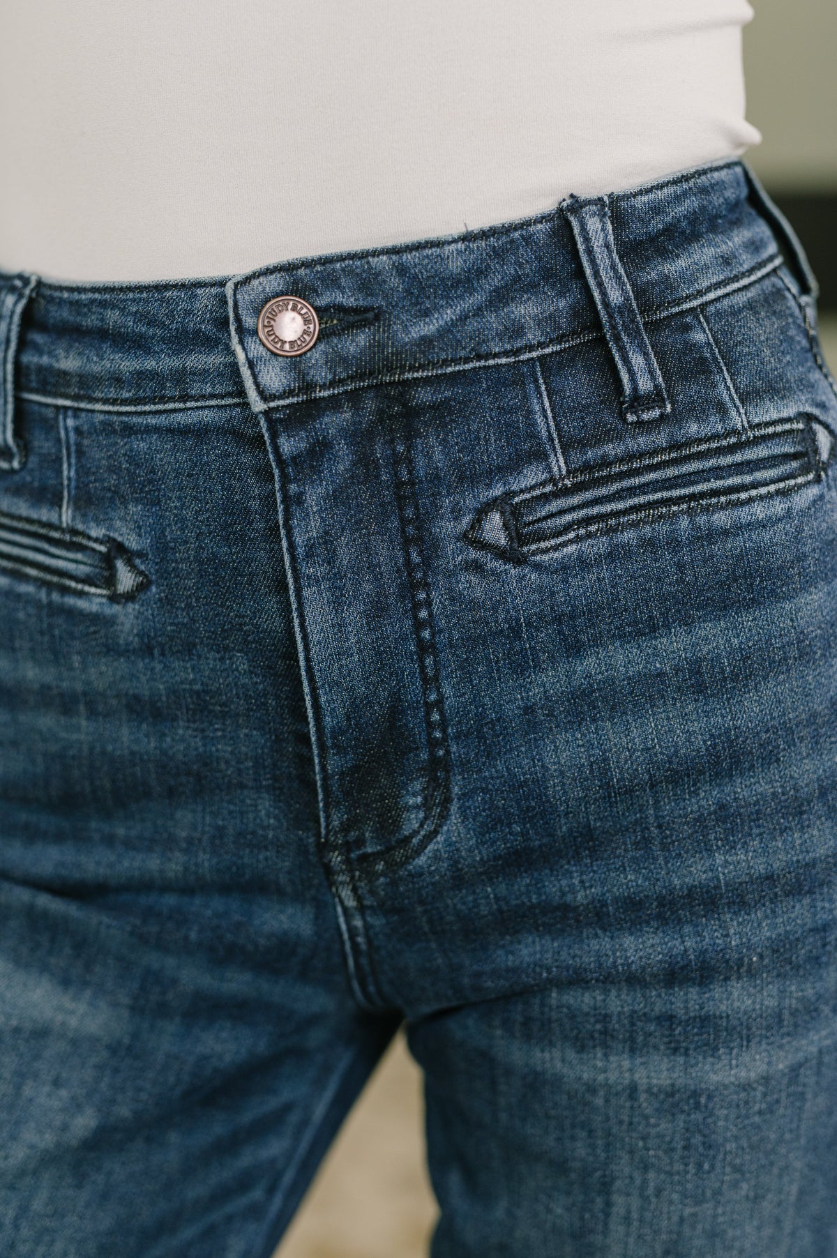 High-waist bootcut jeans waistband close-up with button, belt loops, and front pockets