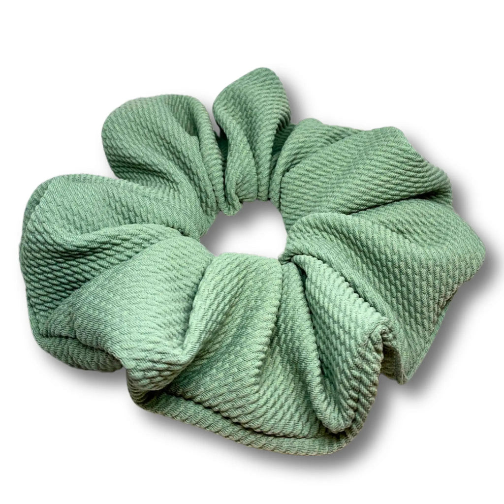 Sage green scrunchie with gathered pleats and textured fabric