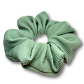 Sage green scrunchie with gathered pleats and textured fabric