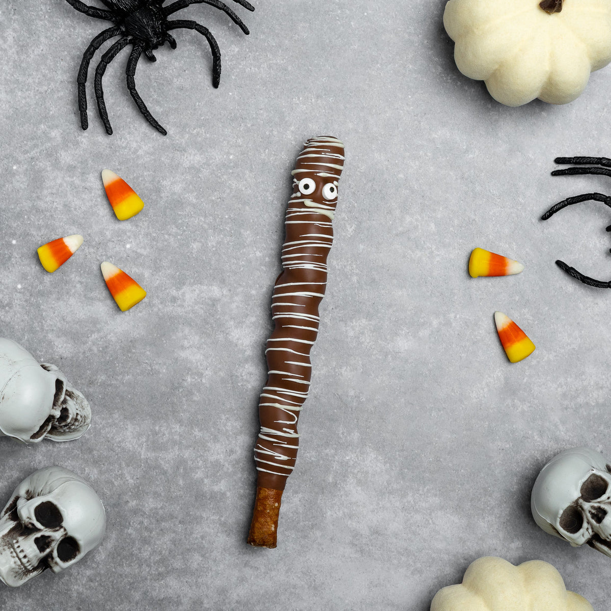 Halloween caramel-brown mummy chocolate pretzel rod with white swirl bandages