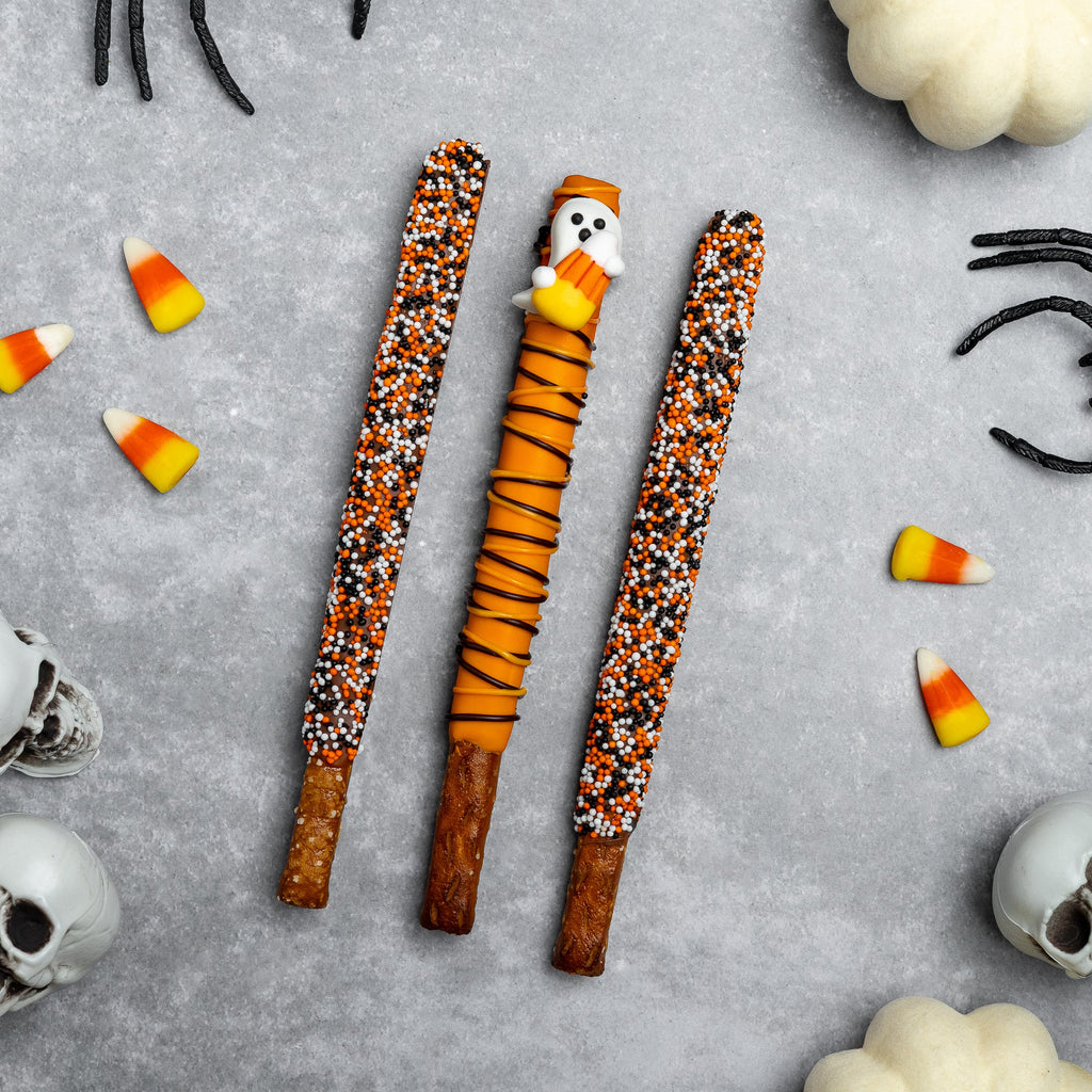 Three Halloween pretzel rods, orange and black sprinkle coating on ridged pretzel