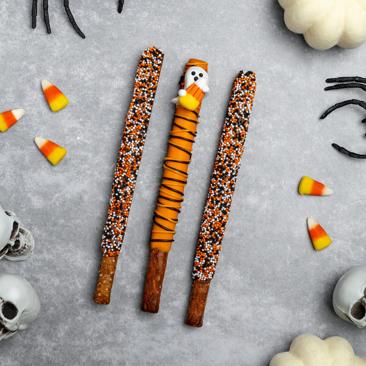 Three Halloween pretzel rods, orange and black sprinkle coating on ridged pretzel