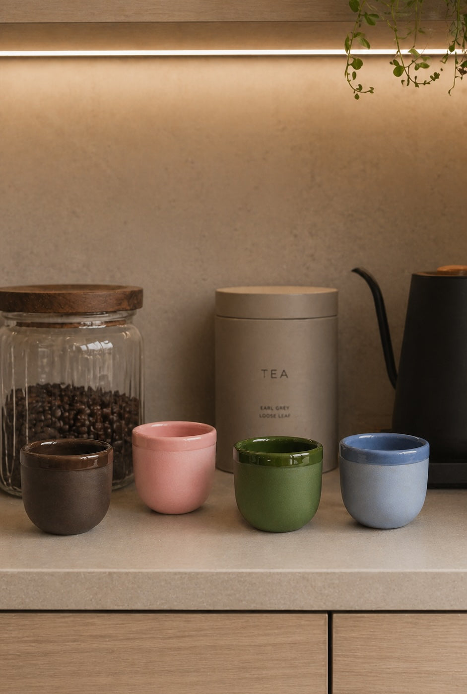 Green, pink, brown, and blue ceramic espresso cups on a shelf, no saucers shown.