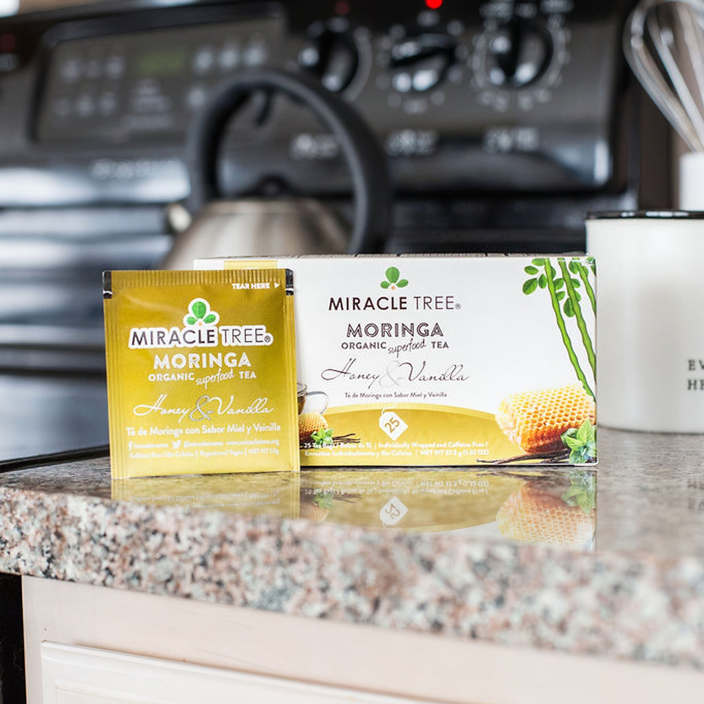 Moringa honey & vanilla herbal tea boxes and sachets on a kitchen countertop.