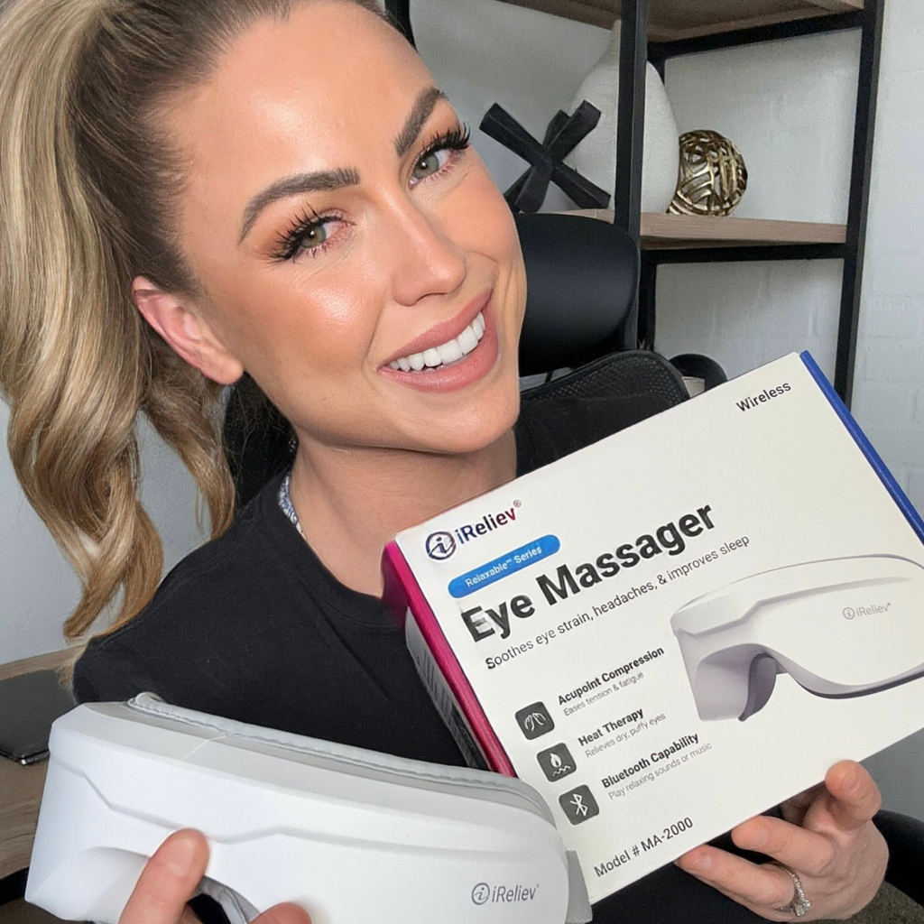 Heated eye massager held near face; gray eye cups and strap visible