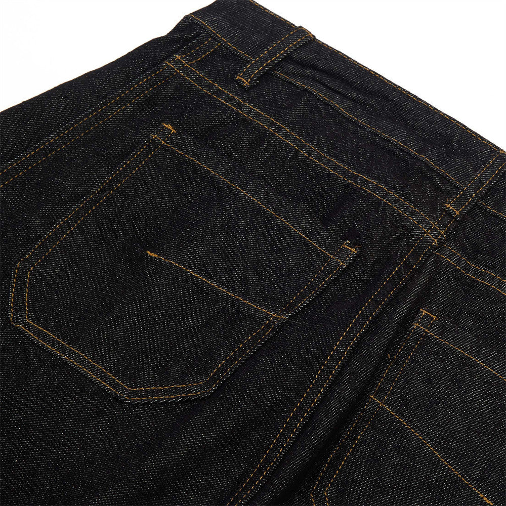 Black denim pants pocket close-up with contrast yellow stitching and curved flap
