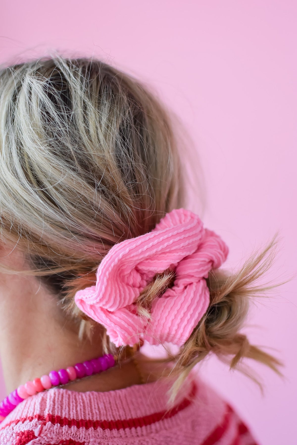 Pink ribbed scrunchy securing a low ponytail