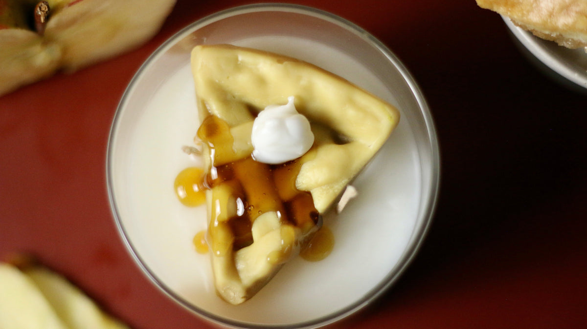 Apple pie candle in clear container with wax crust pieces, dollop, and caramel drizzle