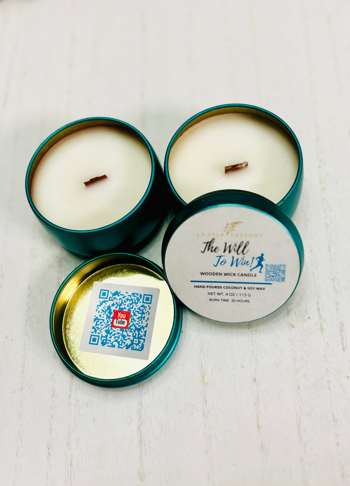Wood-wick candle set in teal tins; lid labeled The Will to Win.