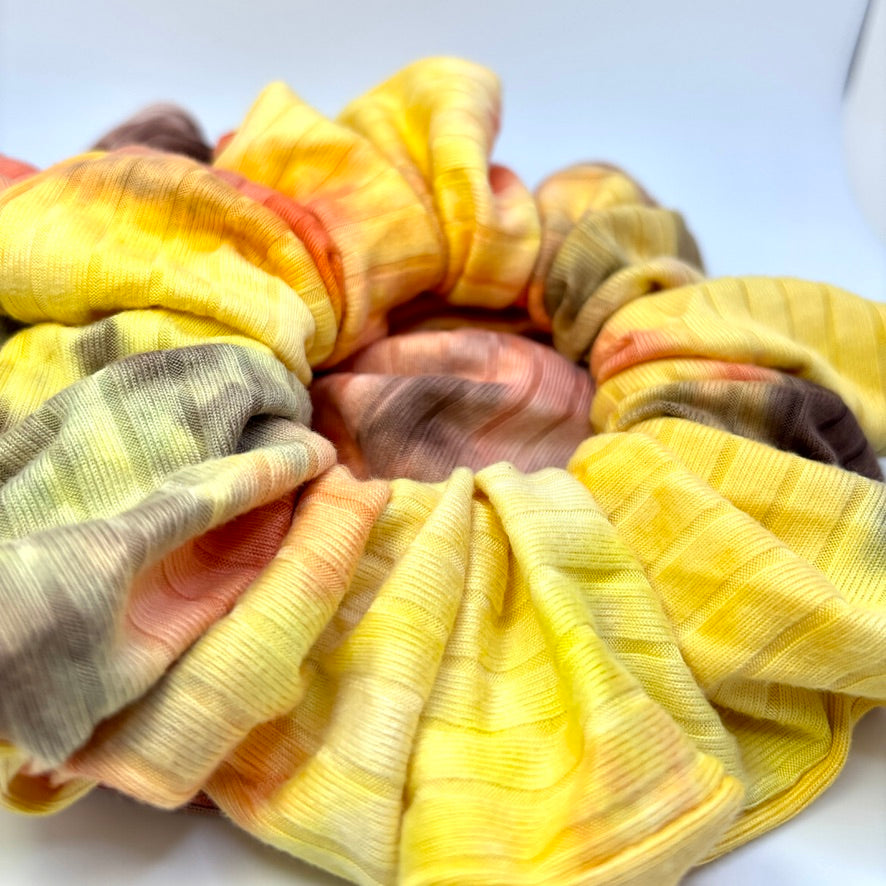 Close-up ribbed tie-dye scrunchie in bright yellow with orange accents