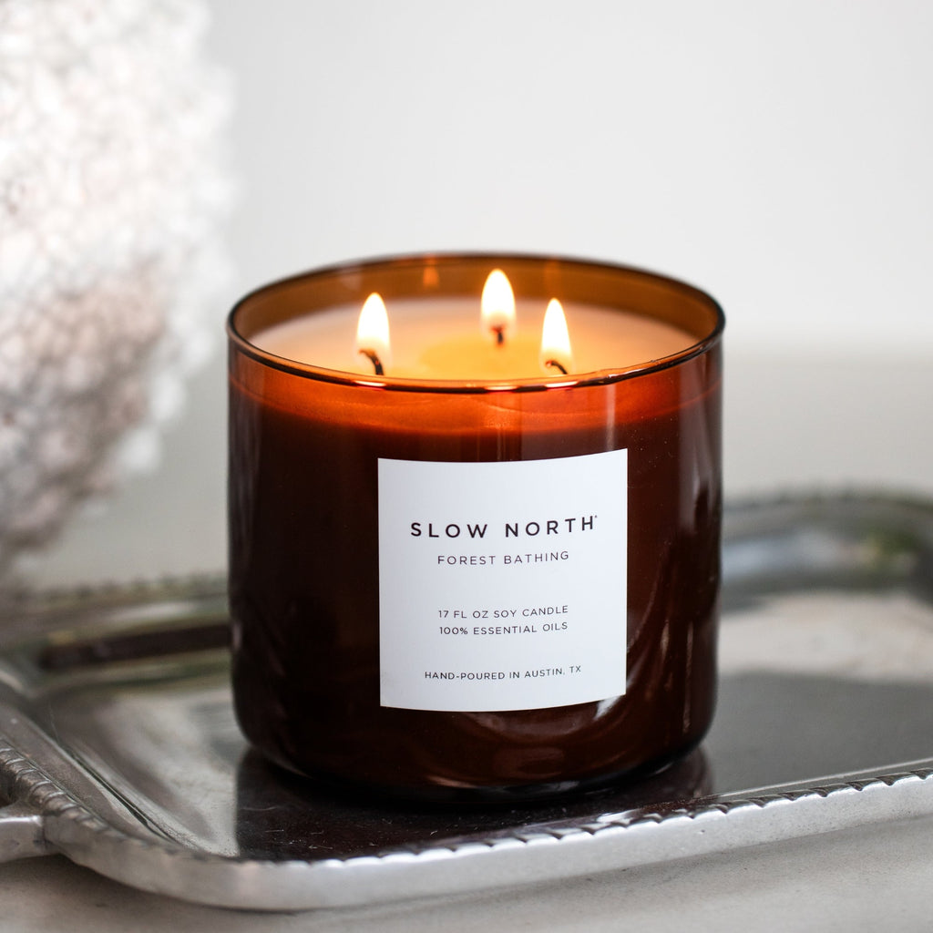 Amber glass 3-wick candle with three lit flames and white front label