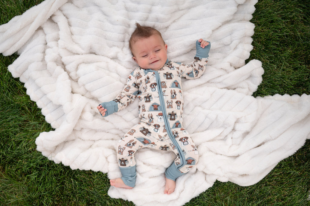 Baby in cream dog-print convertible zip footie pajama with blue-gray zipper trim