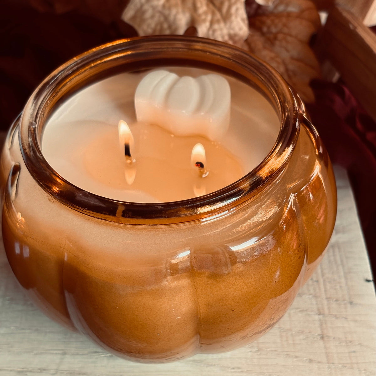 Amber soy candle in glass jar with lit wicks and white wax swirl at center