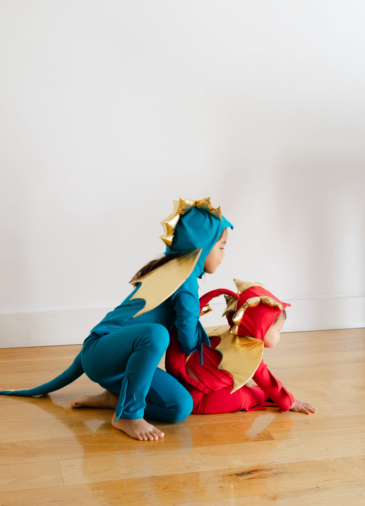 Jade blue dragon costume with gold edge hood spikes and tail detail, worn kneeling