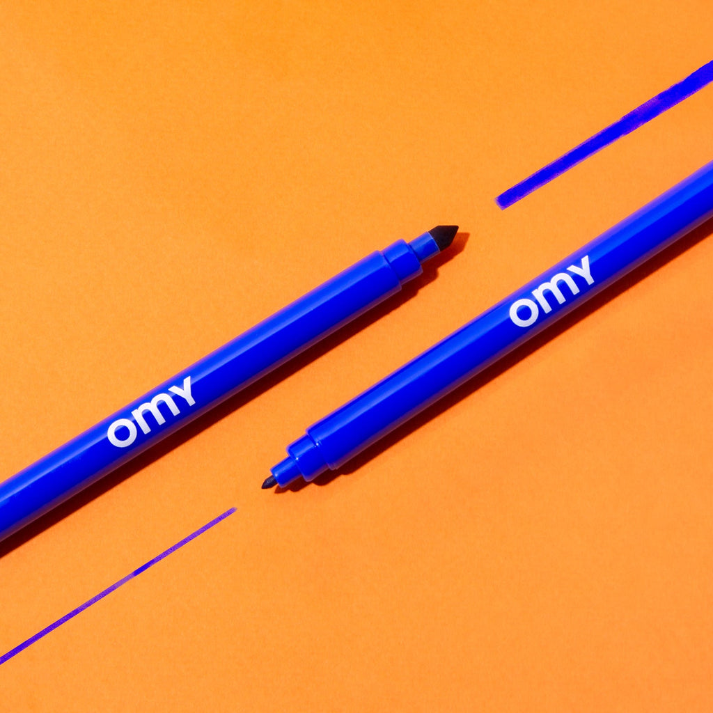 Blue marker pens with chisel tips and omy branding, close-up