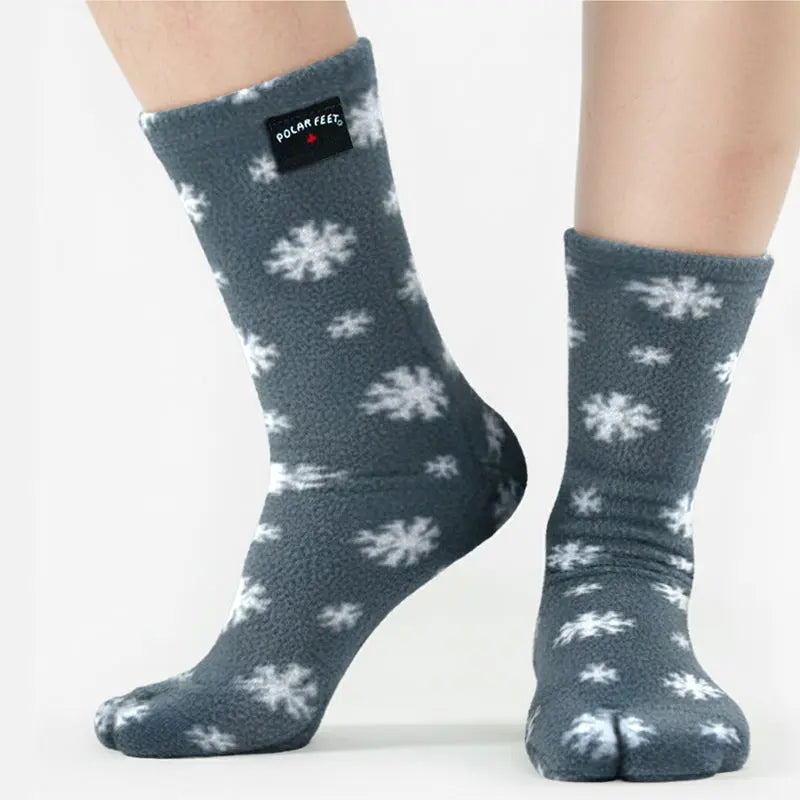 Dark gray fleece tabi socks with white snowflake pattern and logo patch near cuff