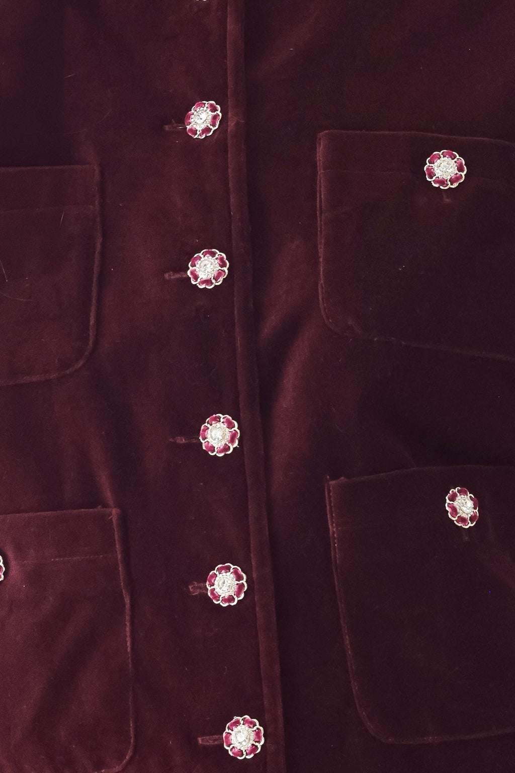 Burgundy velvet jacket detail with jeweled round buttons and patch pockets