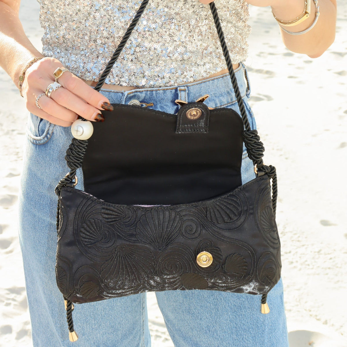 Black shoulder bag with starfish emblem and gold-tone clasp, worn on the shoulder