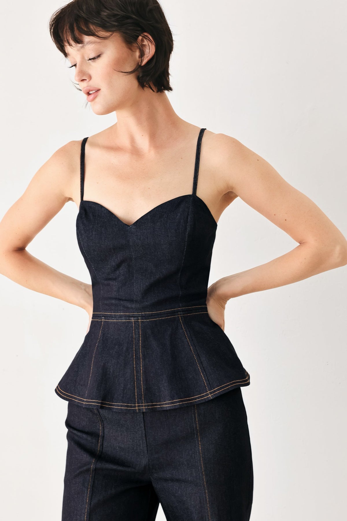 Dark denim jumpsuit with thin straps, sweetheart neckline, peplum hem, wide legs