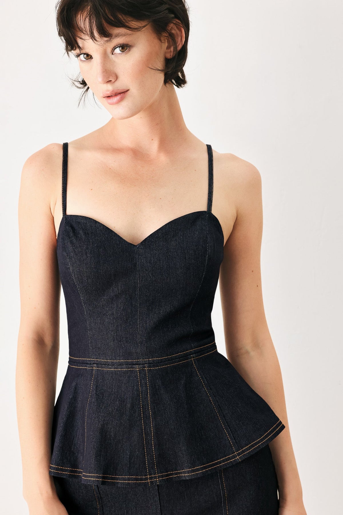 Dark denim corset-style jumpsuit with sweetheart neckline and peplum waist