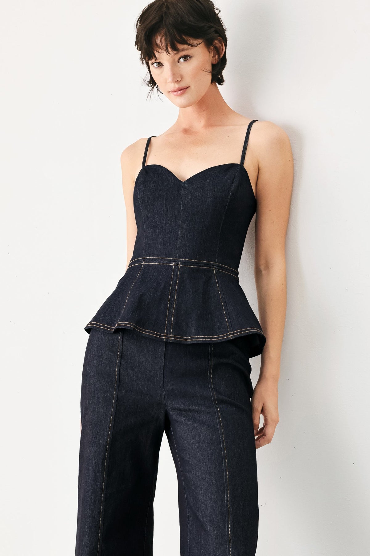 Dark denim jumpsuit with sweetheart neckline, peplum flare, wide-leg pants
