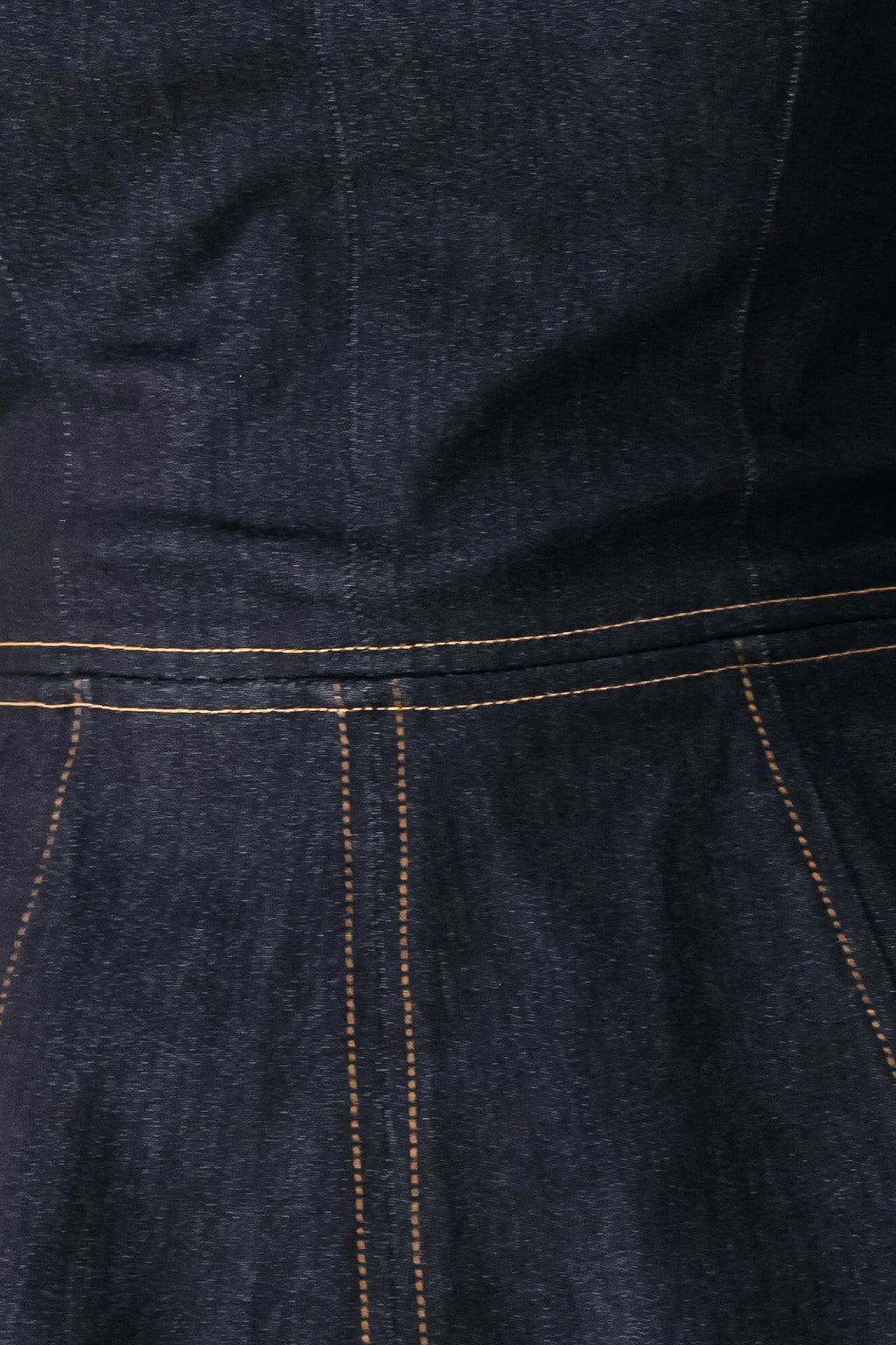Dark denim close-up: stitched yoke and peplum panel with contrast yellow thread