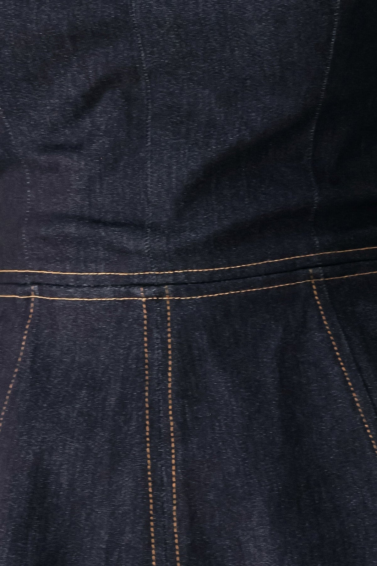 Dark denim close-up: stitched yoke and peplum panel with contrast yellow thread